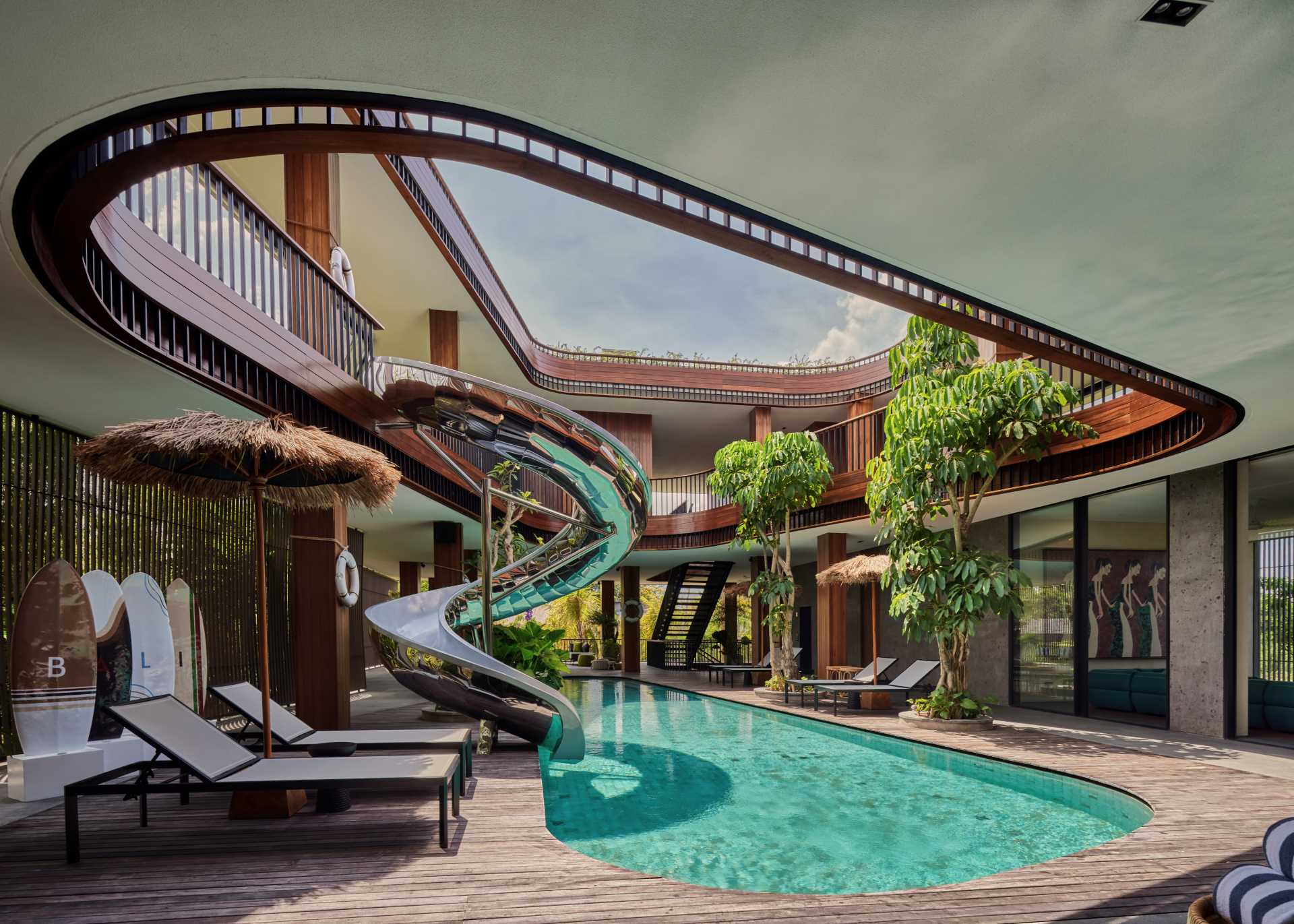 A modern house with multiple floors that's built around a swimming pool with a slide.