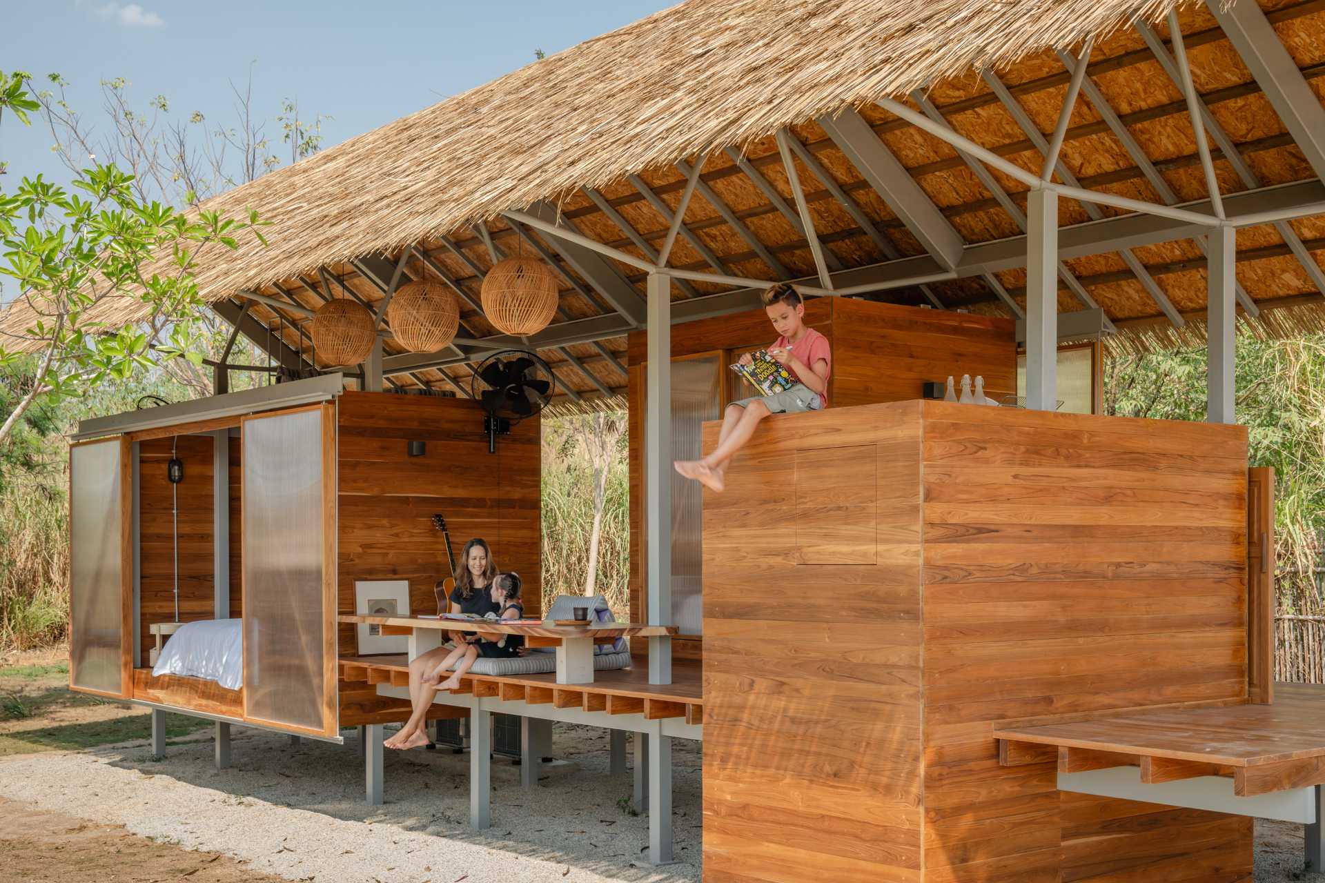 This small cabin designed for children, consists of two compact bedrooms, a shared bathroom, and an open-air deck that serves as a communal living space, blurring the boundary between indoors and outdoors.