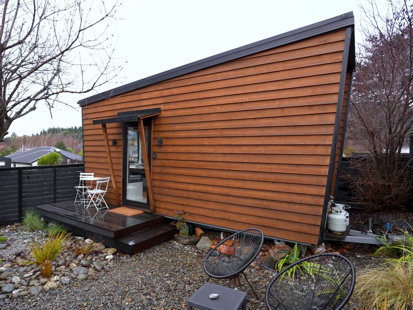 The exterior of this tiny home is clad in timber with black detailing along the edges, giving it a modern cabin feel.
