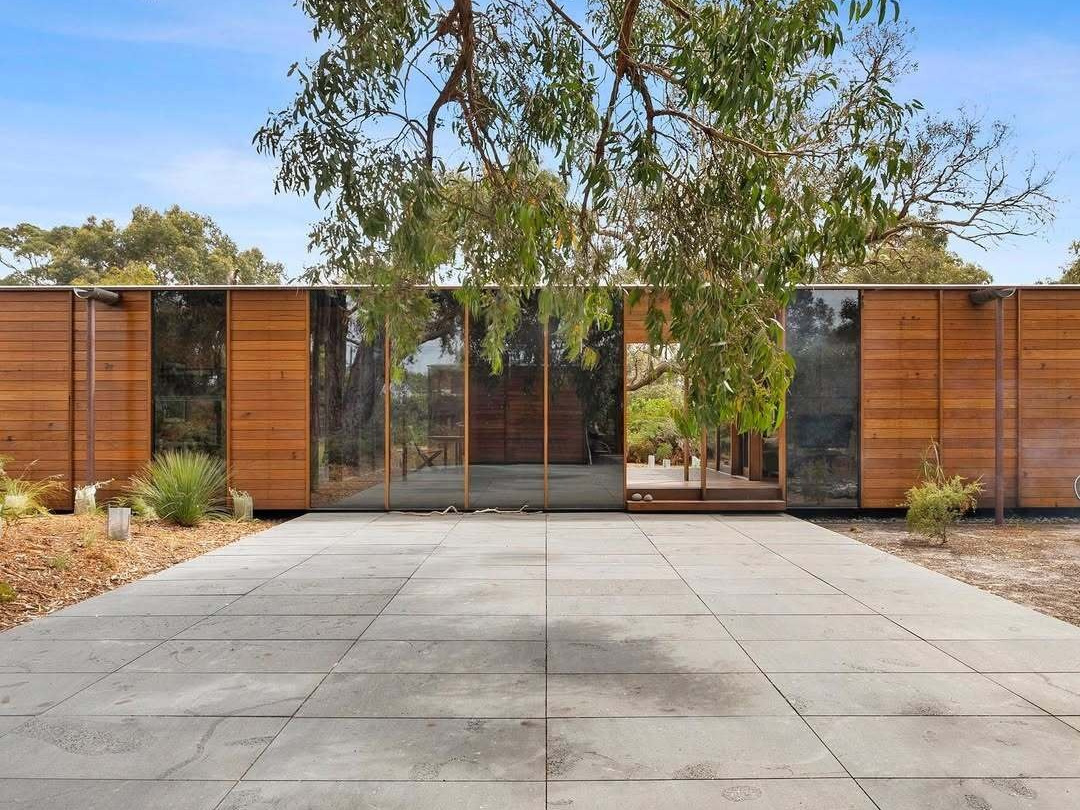 A recycled timber home and studio built with passive solar principles and reclaimed materials. It features two pavilions, full-height glazing, and a bluestone terrace set beneath native trees.