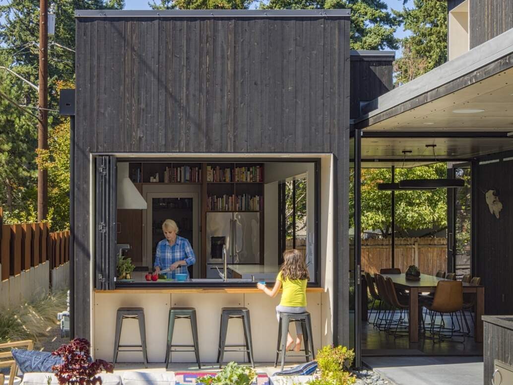 The kitchen opens directly to the courtyard through folding windows. This pass-through setup allows food and drinks to move easily between indoors and out, reinforcing the idea of the home as a continuous, adaptable space.