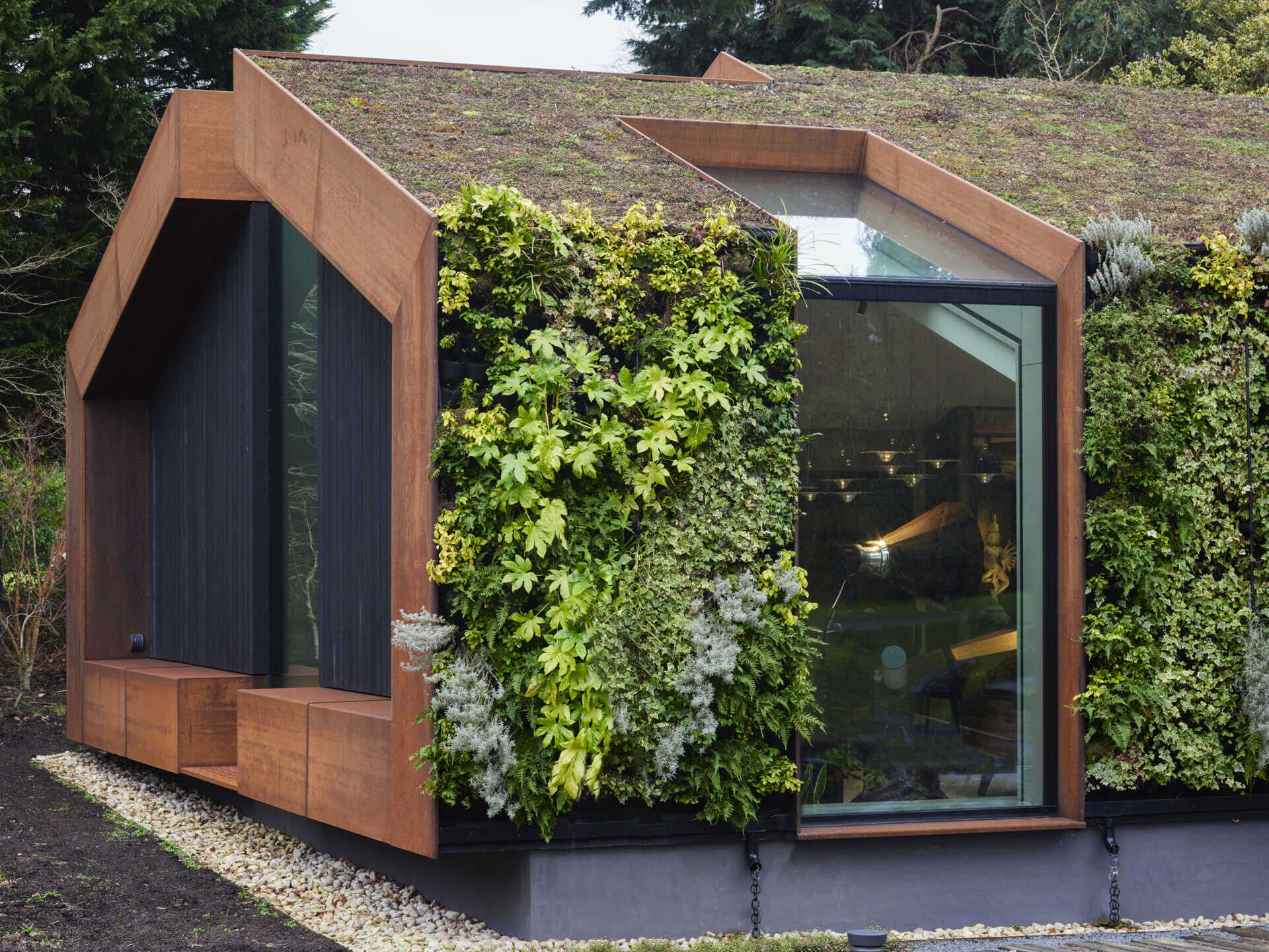 This modern music pavilion blends charred timber, Corten steel, and a living roof to create a sculptural retreat in the landscape. 