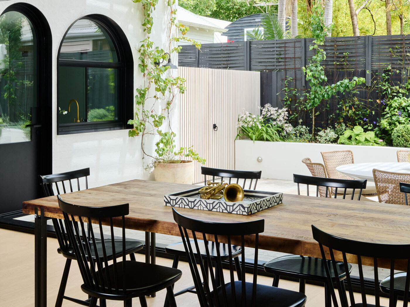 This tranquil alfresco area transforms a former garage wall into a cozy garden retreat. Layered planting, a timber pergola, and a built-in BBQ make it perfect for relaxing or entertaining outdoors.