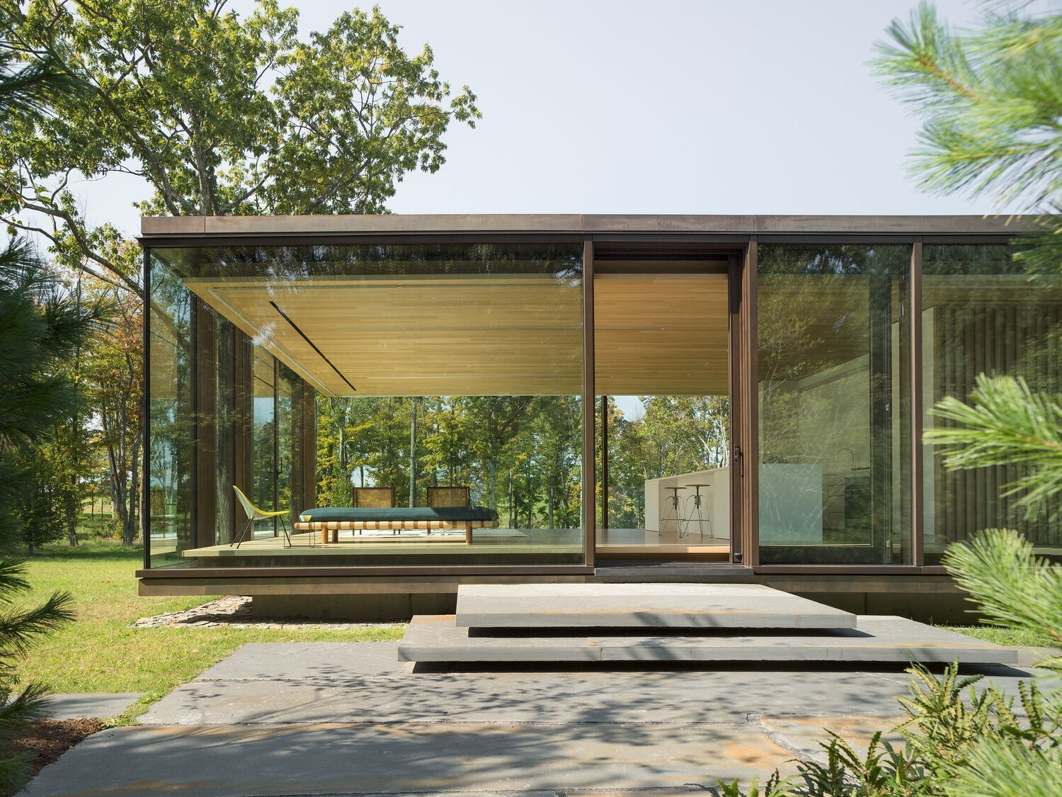 A striking glass guest house with a slatted wood core, cantilevered roof, and high-performance triple-pane glazing, designed to sit lightly on the land.
