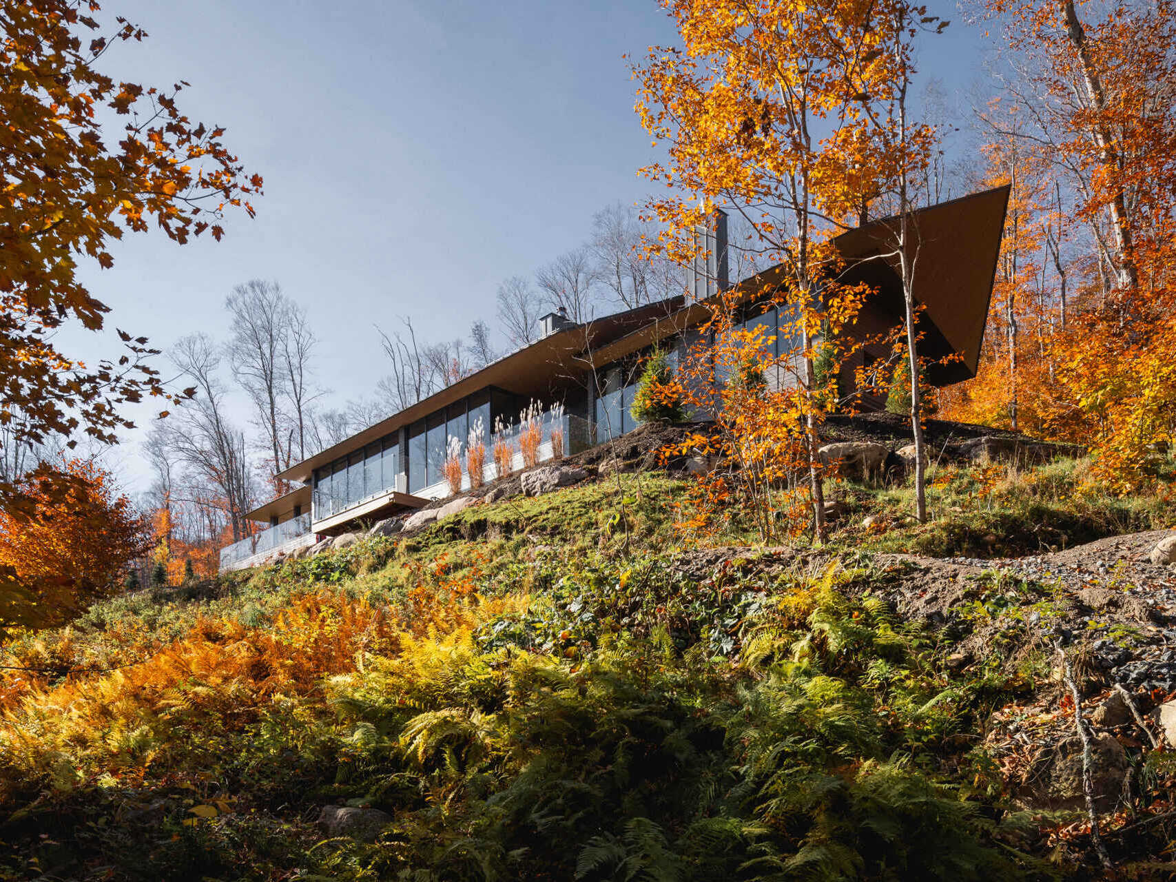 A striking modern chalet by MU Architecture, La Flèche is a forest retreat on Lake Tremblant that blends sharp rooflines, natural stone, and warm wood interiors.