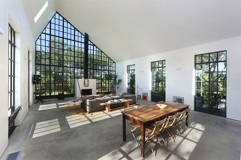At one end of this guest house, dramatic double-height windows shape the exterior. These tall panes of glass give the home a lantern-like glow at night while framing garden views during the day.