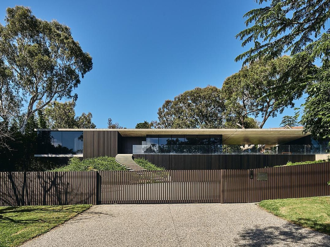 A modern home with a bold, low-profile form that follows the hillside contours, pairing travertine, concrete and glass for timeless appeal.