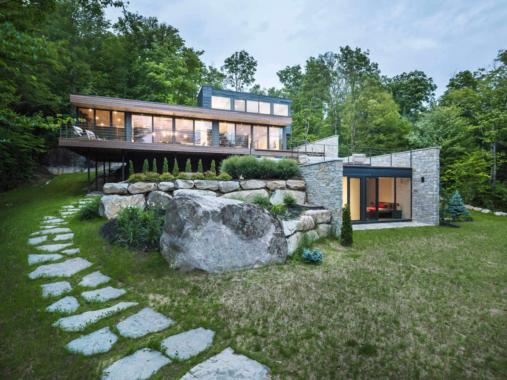 Terraced outdoor spaces framed by natural stone walls blend this modern home seamlessly into its rocky setting.