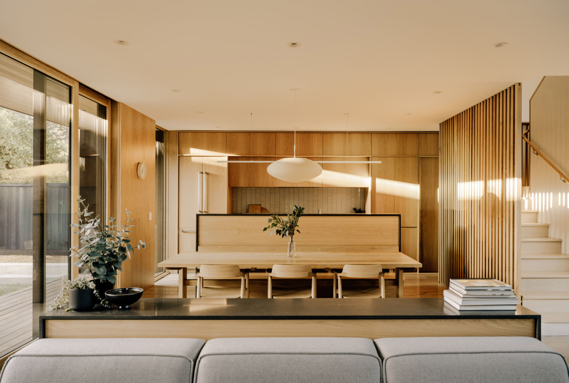 Natural clay plaster walls and warm wood tones create a welcoming hub. Floor-to-ceiling doors open to the courtyards, bringing sunlight, greenery, and fresh air deep into the living areas. The space encourages informal gatherings while maintaining a serene connection to the outdoors.