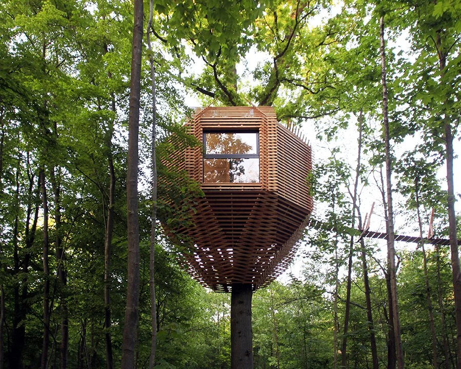 A stunning wooden treehouse by Atelier LAVIT, designed around a century-old oak with an elegant, nest-like form that blends seamlessly into the forest.