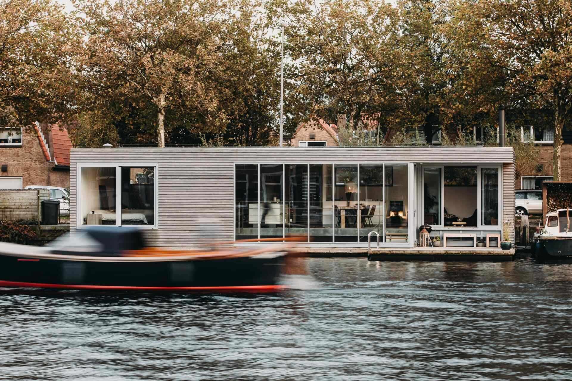 A striking floating villa on the Spaarne with textured wood cladding, slim aluminum trim and bright southwest light shaping the entire design.