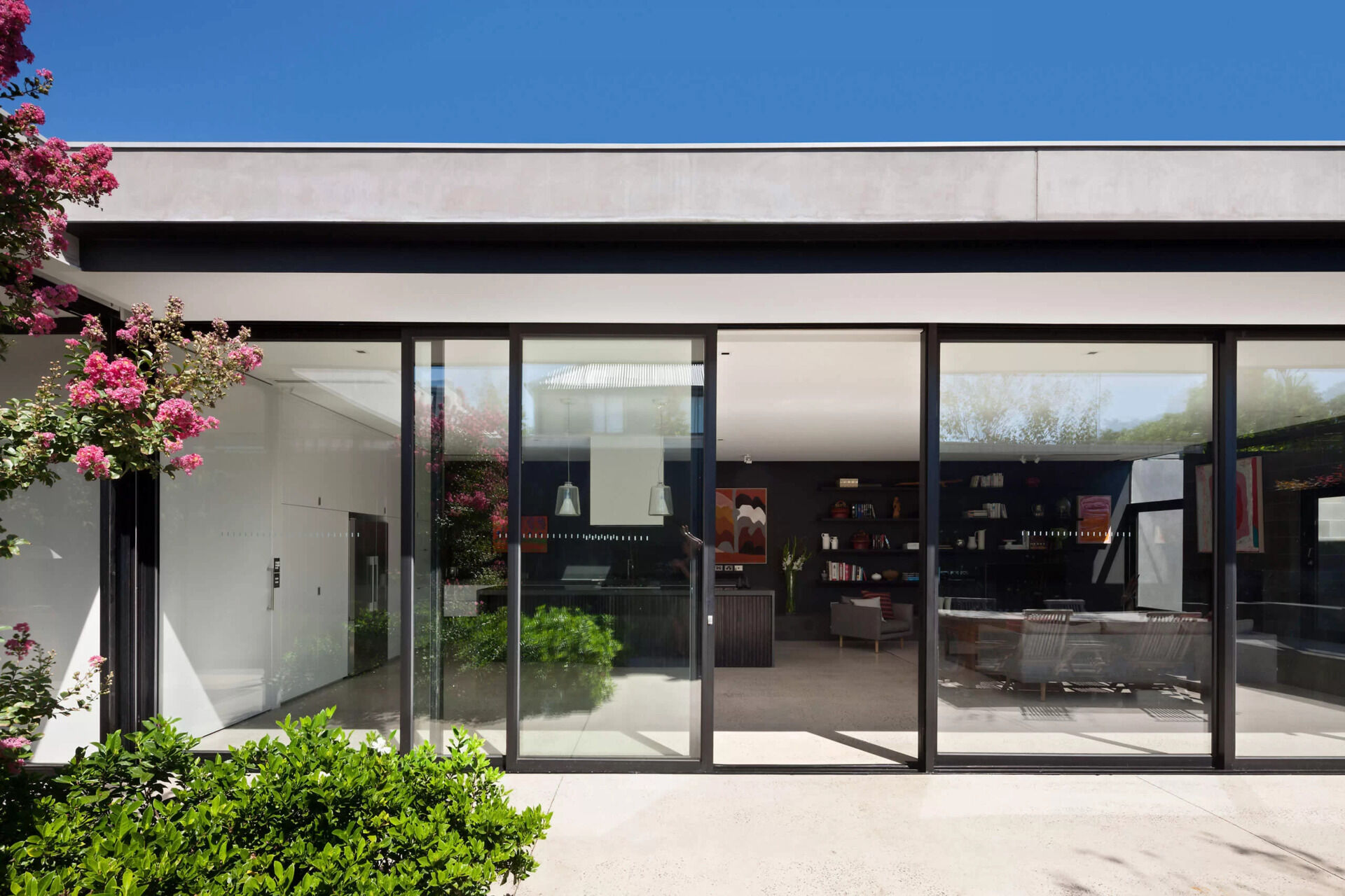 A glass front door opens to an internal garden, setting the tone for an indoor outdoor home filled with greenery.